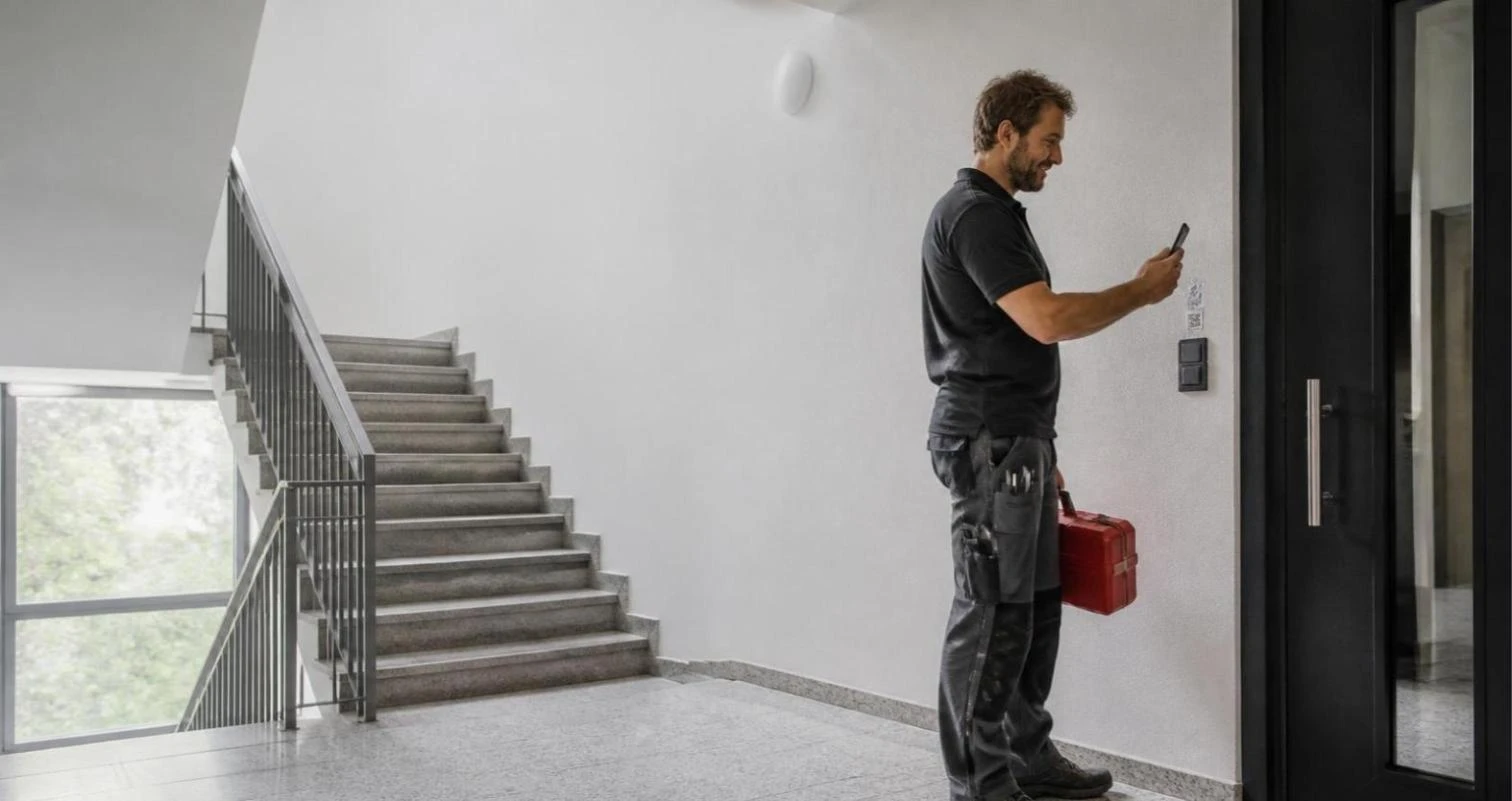 Hausmeister scannt QR-Code im Treppenhaus